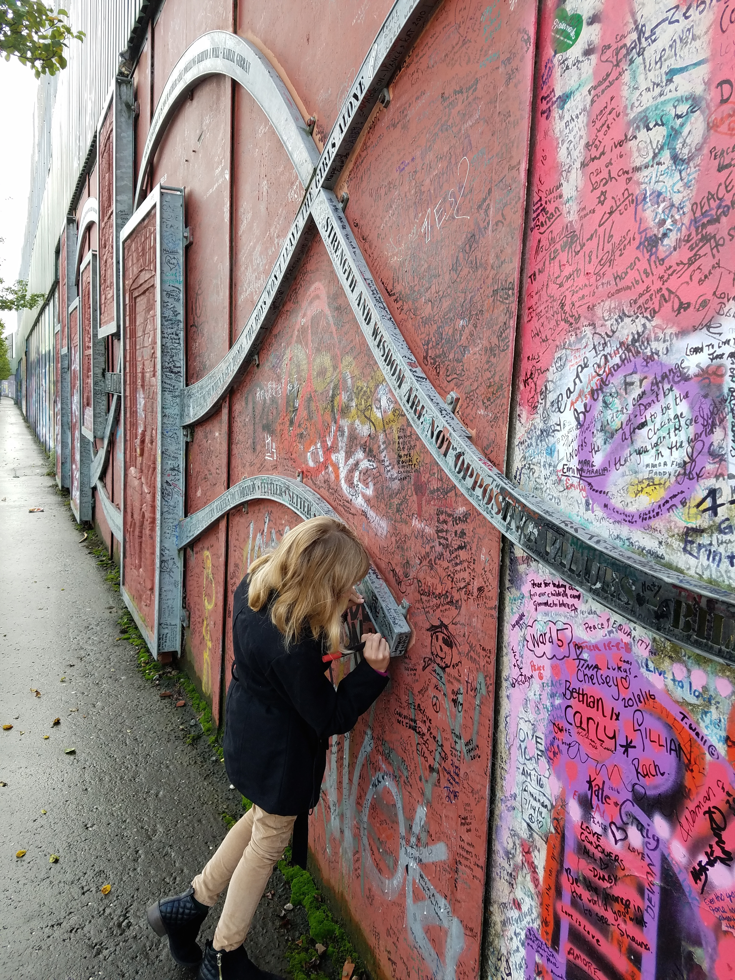 Adding her signature to the peace wall 